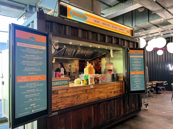 a storage container converted to a food stall with menu boards